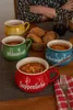 A table setting with four soup bowls filled with soup, bread rolls in a basket, and a glass of red wine. Voir les images du produit
