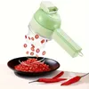 A green electric vegetable cutter is shown slicing red chili peppers into a black bowl. Náhled obrázku produktu