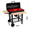 A black charcoal grill with wooden side shelves and a red cooking surface, shown with dimensions indicated by text overlays. Náhľad obrázku produktu