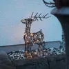 A wire reindeer decoration with LED lights sits on gravel in front of a textured wall. Podgląd zdjęcia produktu