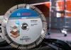 A close-up of a Bosch diamond cutting disc for multi-material use, with a blurred industrial background. Voir les images du produit