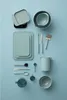 A collection of kitchen utensils and containers laid out on a light blue background. Produktbild-Vorschau