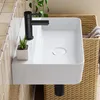 A modern bathroom sink with a black faucet and a small plant. Anteprima dell’immagine prodotto