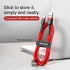 A red charging cable is coiled and secured with a velcro strap, resting on a laptop. Produktbild-Vorschau