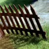 A close-up view of a brown wooden picket fence in a grassy area. Náhľad obrázku produktu