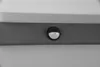 A close-up shot of a motion sensor light mounted on a dark gray horizontal beam, with a white surface above it. Voir les images du produit