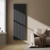 A modern living room with a dark gray vertical radiator next to a window and a beige sofa with a brown throw blanket. Anteprima dell’immagine prodotto