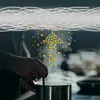 A person is cooking at a stove with steam rising from a pot. Abstract particles and lines are superimposed. Produktbild-Vorschau