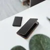 A black leather phone case and a black power bank are placed on a white table. Produktbild-Vorschau