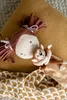 A plush doll and a small monkey toy are resting on a textured yellow surface, with a patterned fabric underneath. Produktbild-Vorschau