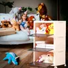 A young girl sits on a couch surrounded by stuffed animals, with a storage cabinet in the foreground. Anteprima dell’immagine prodotto