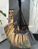 A hanging chair made from coffee sacks and blue fabric, suspended in front of a modern fireplace with stacked wood and a marble wall. Produktbild-Vorschau