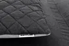 A close-up of a quilted dark gray fabric with a light gray border and a white label with black text. Produktbild-Vorschau