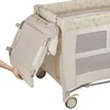 A hand is shown adjusting a side panel of a baby crib/playpen. Produktbild-Vorschau