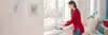 A woman is applying weather stripping to a window frame. Podgląd zdjęcia produktu