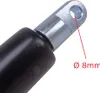 Close-up of the end of a gas spring, showing a metal eyelet with a hole and a black cylinder. Produktbild-Vorschau