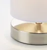 Close-up of the base of a table lamp, showing the metallic base and the bottom edge of the fabric lampshade. Produktbild-Vorschau