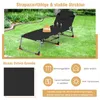 A black folding lounge chair is set up on a grassy lawn in a garden setting. Podgląd zdjęcia produktu