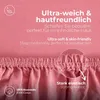 A close-up of pink fabric, likely a bedsheet, with text overlays highlighting its features. Produktbild-Vorschau