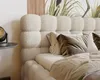 A close-up view of a bed with a textured headboard and pillows. Náhled obrázku produktu