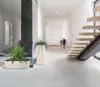 A modern hallway with a staircase and plants. Voir les images du produit