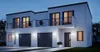 A modern, white, two-story house with a balcony, garage doors, and exterior lighting at dusk. Anteprima dell’immagine prodotto