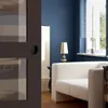 A modern living room with a dark gray door in the foreground and a blue wall, white sofa, and a lamp in the background. Produktbild-Vorschau