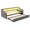 A grey sofa bed with its pull-out trundle bed extended, showing the wooden slats of both beds. The back of the sofa has integrated yellow LED lighting. Produktbild-Vorschau
