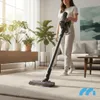 A woman is vacuuming a carpet in a bright, modern living room with plants and furniture. Podgląd zdjęcia produktu