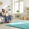 A family is sitting on a couch in a living room, looking at a laptop. Produktbild-Vorschau