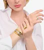 A close-up shot of a woman's arm and hand wearing jewelry, including bracelets and rings. Anteprima dell’immagine prodotto