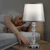 A woman is sleeping in bed, reaching for a table lamp with USB charging ports. Produktbild-Vorschau