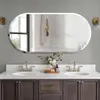 A modern bathroom vanity with a large oval mirror above it, featuring two sinks and faucets. Voir les images du produit