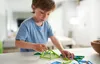 A young boy is playing with magnetic building toys on a white table. Náhled obrázku produktu