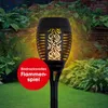 A solar-powered garden torch with a flame effect, set in a garden at dusk. Produktbild-Vorschau