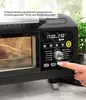 Close-up of a black electric oven with a digital display and controls. A hand is pressing a button on the control panel. Anteprima dell’immagine prodotto