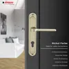 A close-up of a nickel-colored door handle on a dark gray door, with a blurred interior scene visible through an open doorway. Produktbild-Vorschau