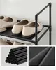 Close-up of a black multi-tier shoe rack with beige shoes on one of the shelves. Náhled obrázku produktu