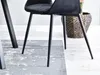 Close-up of the legs of a black dining chair on a rug. Náhled obrázku produktu