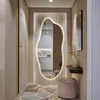 A modern hallway with a large, organically shaped mirror illuminated by LED lights, a small shelf with a vase, and a round stool. Náhľad obrázku produktu