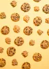 A collection of chocolate chip cookies and caramel clusters arranged on a yellow background. Produktbild-Vorschau
