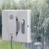 A white window cleaning robot is attached to a window covered in soap suds and water streaks. Produktbild-Vorschau