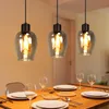 Three pendant lights hang over a wooden dining table set with plates and glasses. Produktbild-Vorschau