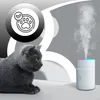 A gray cat sits next to a white humidifier emitting mist, with a circular graphic featuring a paw print and checkmark in the background. Produktbild-Vorschau