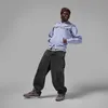 A young man posing in a studio setting, wearing a purple zip-up hoodie, dark wash baggy jeans, and brown sneakers. He is also wearing a brown beanie. Náhled obrázku produktu