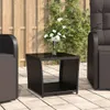 An outdoor patio scene with a wicker side table holding a vase of white calla lilies, next to outdoor furniture. Produktbild-Vorschau