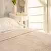 A close-up view of a bed with a beige striped blanket and a white pillow. Anteprima dell’immagine prodotto