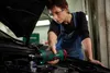 A woman is working on a car engine, using a cordless ratchet tool. Podgląd zdjęcia produktu