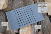 A metal grate with holes is placed on a pile of firewood. Dimensions and model information are displayed with text overlays. Voir les images du produit