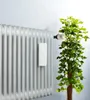 A white ceramic air humidifier with a floral pattern is attached to a radiator, next to a green plant. Podgląd zdjęcia produktu